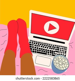 Woman lies on the bed and watches series on laptop with popcorn in her cute room.