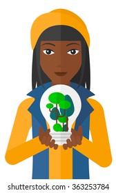 Woman with lightbulb and trees inside.