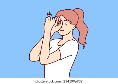 Woman looks through invisible spyglass with curiosity and wanting to know what is happening in distance. Inquisitive girl feels curiosity and puts hands to eyes watching world around her.