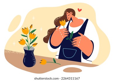 Woman in love smells flower given by guy on date and dreams of quick meeting or marriage. Girl inhales scent of tulips while standing near vase with bouquet of flowers presented for birthday 