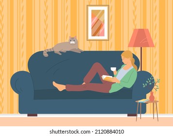 Woman lying on couch with interesting book. Girl resting at home and reading literature. Lady lies on sofa with cat and book. Person spends time on furniture. Recreation, leisure activity concept
