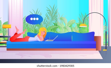 woman lying on sofa and using laptop chat bubble communication social media network concept