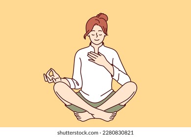 Woman meditates with hand on heart and wishes to heal herself through yoga and Buddhist spiritual practices. Girl sitting in lotus position takes care of heart chakra and relaxes during yoga 