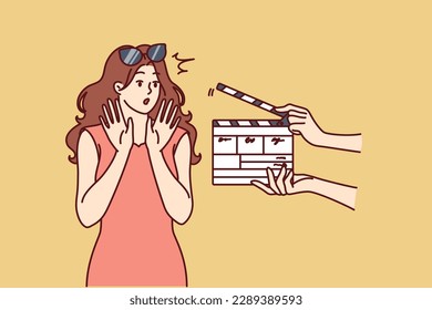 Woman movie star is embarrassed sees clapboard passing casting call for role in popular series or tv show. Movie star girl waving hands, not wanting to film or answer questions from reporters 