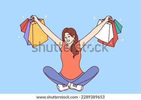 Woman with multi-colored packages from clothing stores sits with her arms apart after successful shopping. Girl who won shopping lottery shows off things purchased at big discount or cashback 