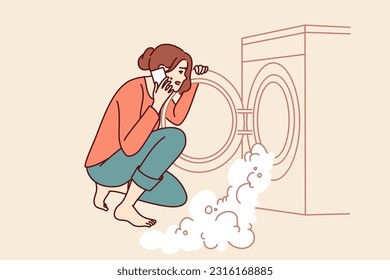 Woman near broken washing machine calls home electronics repairman because of foam pouring out of drum. Excited housewife sitting looking at washing machine with factory defect causing leak