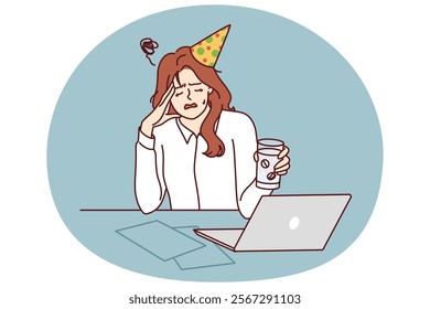 Woman office worker suffers from hangover after party and drinks pills to relieve headache. Girl in birthday hat and business clothes sits at table with laptop experiencing hangover in workplace