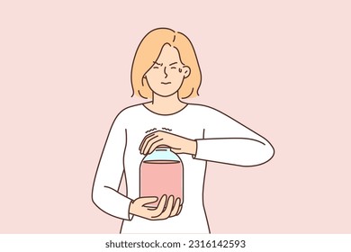 Woman opens jar of juice or compote, trying to unscrew tight jammed lid. Weak girl dressed in casual clothes closes eyes and makes effort to open glass jar with delicious fruit drink