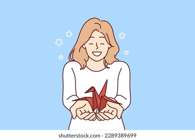 Woman with origami crane in palms wants to draw attention to problem of wildlife and extinction of animals from red book. Positive smiling girl holding origami bird for creative hobby concept 