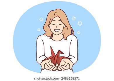 Mujer con grúa de origami en las palmas quiere llamar la atención al problema de la vida silvestre y la extinción de los animales del libro rojo. Chica sonriente positiva que sostiene el pájaro del origami para el concepto creativo de la afición