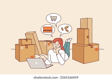 Woman owner of online store is engaged in e-commerce, lying on floor with laptop among cardboard boxes. Girl makes money on e-commerce, thanks to digital retail technologies and delivery services