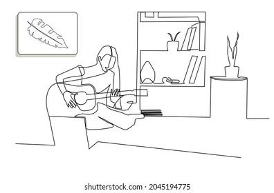 Woman playing guitar in front of computer at home. Girl taking guitar lessons online. The lady who makes music as a hobby at home.