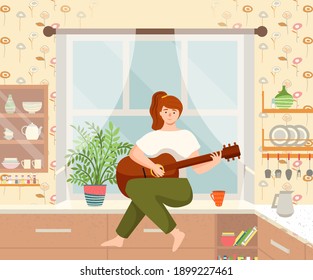 Woman is playing the guitar sitting on the kitchen table. Musician composes songs and sings at home. Female character makes music indoor. Person is fond of creativity sings songs, hobby time relaxing