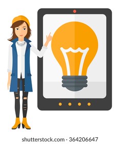 Woman pointing at tablet computer with light bulb on screen.