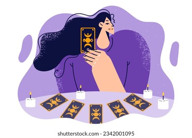 Woman predictor with tarot cards laid out on table with candles predicts future during esoteric session. Predictor or fortune teller uses magical paraphernalia to perform spiritualistic procedures