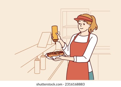 Woman prepares hot dog working as seller in street food cafe or restaurant on wheels with delicious sandwiches on menu. Girl who works in fast food industry adds mustard to hot dog ordered by client.