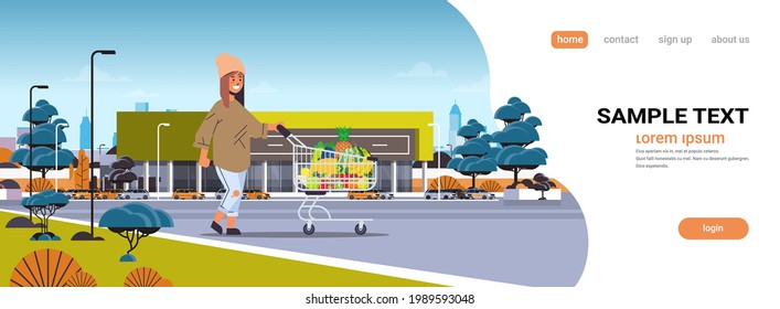 woman pushing trolley cart with different sweet tropical fruits healthy lifestyle vegan food concept modern supermarket building exterior horizontal full length copy space