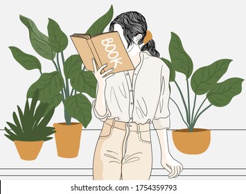 Woman is reading a book in her own house and has a vase of plants.