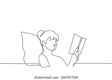 woman is reading a paper book while lying on the bed her head is on the pillow which rests on the headboard - one line drawing vector. bedtime reading concept; book lover with analogue book 