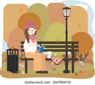 A woman reads a book and has a picnic on a bench next to a trash can and a lamppost at the park in autumn