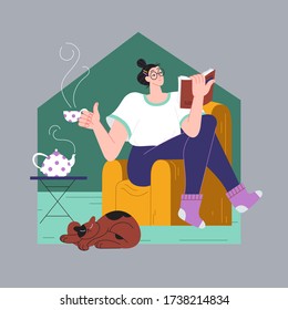 Woman reads a book on an armchair and drinks tea. Pastime during self-isolation.