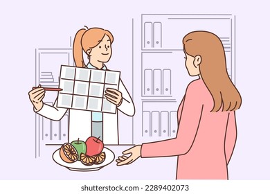 Woman receives advice from nutritionist on proper nutrition and diet to lose weight or improve health. Girl working as nutritionist demonstrates calendar and recommends eating more vegetables