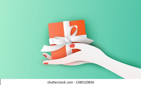 Woman with a red gift box holding in hand to deliver present in Christmas. Merry Christmas and happy new year. paper cut and craft style. vector, illustration.