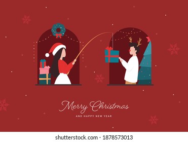 A woman in Santa hat giving a Christmas gift box to a man in reindeer headband by fishing rod. Social distancing concept. Quarantine Christmas card in a covid-19 world. Neighbors at the window.