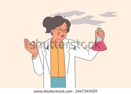Woman scientist experienced failure when mixing reagents, holds smoking test tube in hands. Failure in laboratory research caused explosion in girl scientist standing in white shabby coat