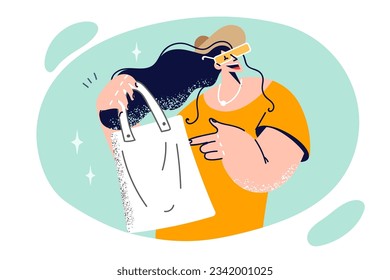 Woman shopaholic holds reusable bag for going to supermarket and smiles calling for abandonment of plastic. Fashionable shopaholic girl uses shopping bag made from recycled materials
