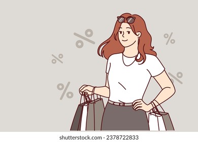 Woman shopaholic returns from store with packages and stands among percent symbols. Shopaholic girl smiles, rejoicing at opportunity to go shopping and visit fashion boutiques with clothes.