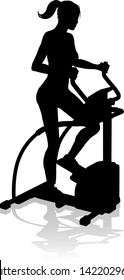 A woman in silhouette using an elliptical cross fit gym equipment exercise machine 