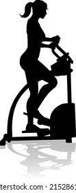 A woman in silhouette using an elliptical cross fit gym equipment exercise machine 