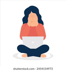 Woman sits at the computer and crying covering her face with her hands.