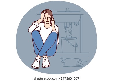 Woman sits near leaking sink making call to plumber to repair broken pipeline. Frightened girl calls sink repairman or emergency service to clean up consequences of flood in bathroom or in kitchen