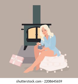 Woman sitting near fireplace with hot cocoa. Romantic cozy mood, christmas present, fluffy warm blanket.