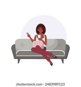 Woman sitting on a couch, holding a phone and making a peace sign with her other hand, with a laptop on her lap. Blogging, social media, home office concept