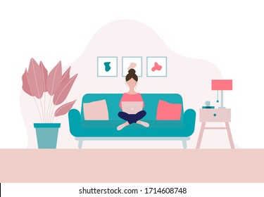 Woman sitting on a sofa with laptop  in her living room in period of self isolation and social distancing during Covid-19 virus epidemic. Stay home concept. Freelance or studying concept.