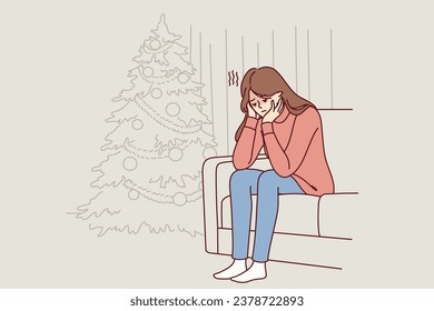 Woman is sitting on sofa near christmas tree and is sad because of loneliness and lack of friends during new year holidays. Christmas melancholy in girl in need of psychological support