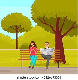 Woman sitting in park on brench holds smartphone in her hand. Casual lady in headpones listening to music and browsing social media on mobile device. Man read news paper in autumn park