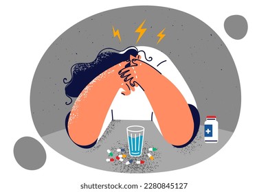 Woman sitting at table with pills suffering from headache or migraine due to overwork or unhealthy lifestyle. Girl suffering from mental problems and drinks lot of medicines to cope with pain in soul 