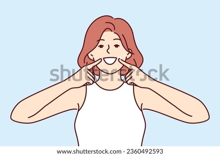 Woman smile and shows off white teeth and points fingers at mouth to invite people to dental clinic. Positive girl is trained to make big smile to appear friendly for successful sales