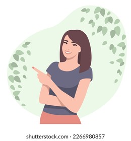 The woman smiles and points her finger to the side against the background of the greenery and leaves of the tree.