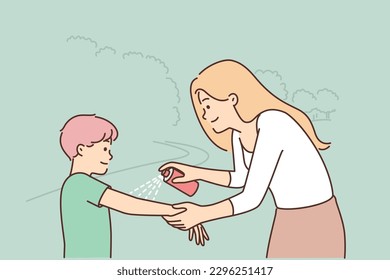 Woman spraying mosquito spray on boy hand taking care of preteen child health walking in park or hiking in nature. Caring young mother using mosquito spray or sunscreen with little son