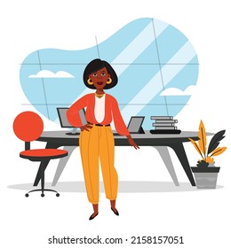  woman standing in her office, behind a desk and glass. 