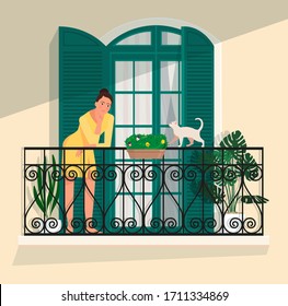 A woman stands on a balcony against a panoramic door with shutters, and a cat walks along the railing.