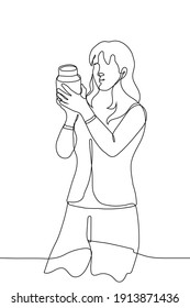 Woman Stands Reading A Label On A Jar. One Line Drawing - Woman Shopper Holds A Jar And Reads The Composition (ingredient) On It.