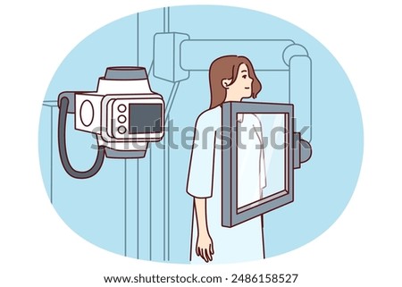 Woman suffering from cancer stands near x-ray machine making medical examination for diagnosing oncological disease. Girl during mammogram for early detection of breast cancer undergoes radiography