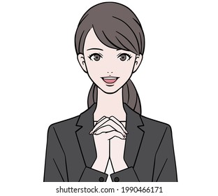 A woman in a suit with her hands folded in front of her chest