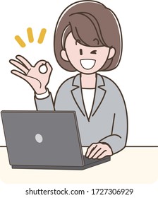 A woman in a suit operating a PC while doing OK sign